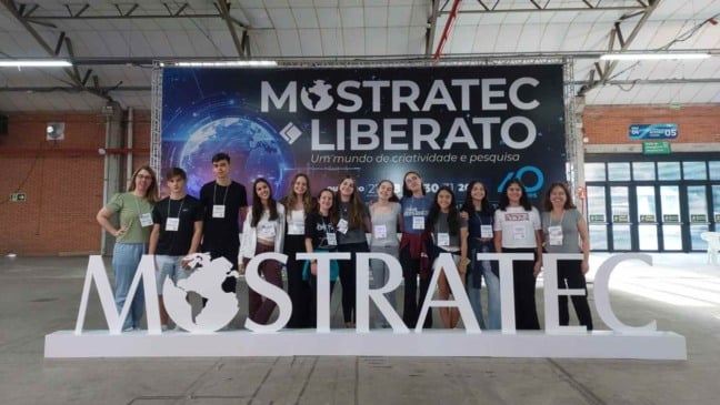 Estudantes do Colégio Degraus segurando a bandeira da escola após participação premiada na Mostratec 2025.