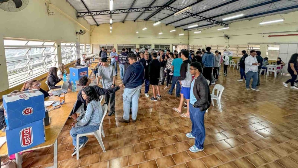 Pessoas em fila sendo atendidas por servidores públicos em ação comunitária da Prefeitura de Jundiaí, realizada em espaço coberto e iluminado. Pessoas em fila sendo atendidas por servidores públicos em ação comunitária da Prefeitura de Jundiaí, realizada em espaço coberto e iluminado.