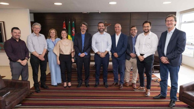 Grupo de autoridades e representantes empresariais posando para foto em sala institucional da Prefeitura de Jundiaí, durante reunião sobre empreendimento sustentável de energia limpa e tecnologia.
