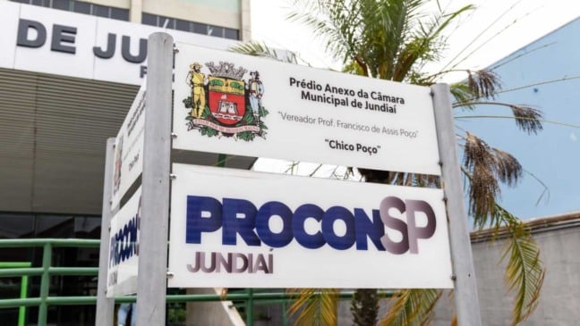 Placa do Procon Jundiaí em frente ao prédio anexo da Câmara Municipal, com brasão da cidade e fachada ao fundo.