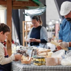Produtor rural atende um menino em banca de queijos, pães e doces artesanais durante o evento Sabores da Gente no Espaço Expressa, em Jundiaí.