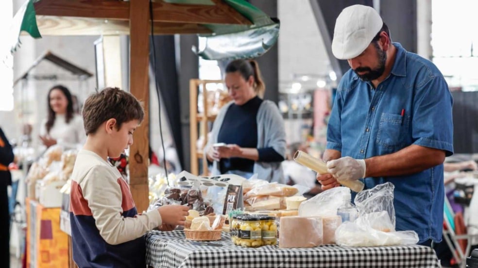 Produtor rural atende um menino em banca de queijos, pães e doces artesanais durante o evento Sabores da Gente no Espaço Expressa, em Jundiaí. Produtor rural atende um menino em banca de queijos, pães e doces artesanais durante o evento Sabores da Gente no Espaço Expressa, em Jundiaí.