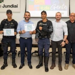 Grupo formado por guardas municipais e representantes da Prefeitura de Jundiaí posando para foto oficial; dois agentes seguram certificados recebidos durante a cerimônia.