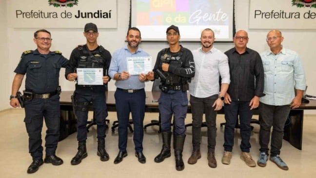 Grupo formado por guardas municipais e representantes da Prefeitura de Jundiaí posando para foto oficial; dois agentes seguram certificados recebidos durante a cerimônia.