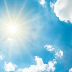 Céu azul com sol forte e nuvens brancas, representando um dia ensolarado e de tempo estável.