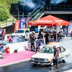 Carros de arrancada fazendo burnout na pista do SPID em Itatiba, com equipes ao redor, fumaça intensa e estrutura do evento ao fundo.