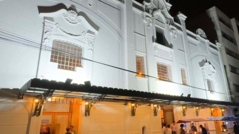 Fachada iluminada do Teatro Polytheama à noite, em Jundiaí, com pessoas reunidas na entrada principal sob a marquise.