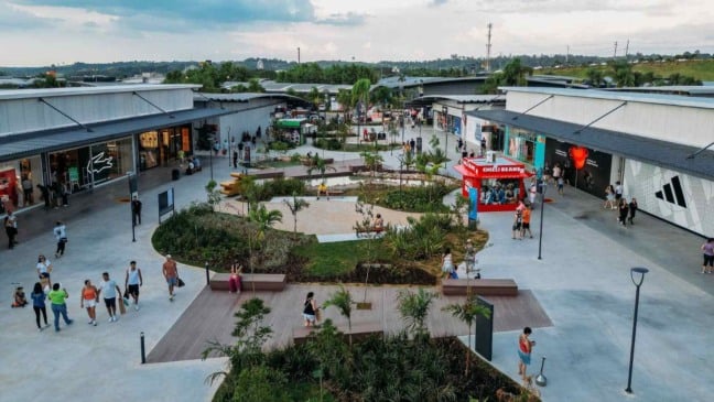 Vista aérea do Outlet Premium São Paulo em Itupeva com visitantes caminhando entre lojas e área ajardinada.
