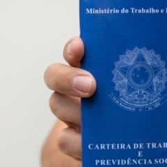 Pessoa segurando uma Carteira de Trabalho e Previdência Social em close, com foco no documento azul.