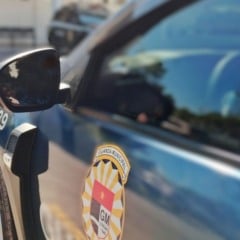 Viatura da Guarda Municipal de Jundiaí vista de perto, mostrando o brasão na porta, com o prédio do Plantão Policial desfocado ao fundo.