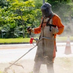 Trabalhador faz ro&ccedil;agem de mato em &aacute;rea p&uacute;blica de Jundia&iacute;, usando equipamento de prote&ccedil;&atilde;o e m&aacute;quina motorizada, durante a&ccedil;&atilde;o de zeladoria urbana.