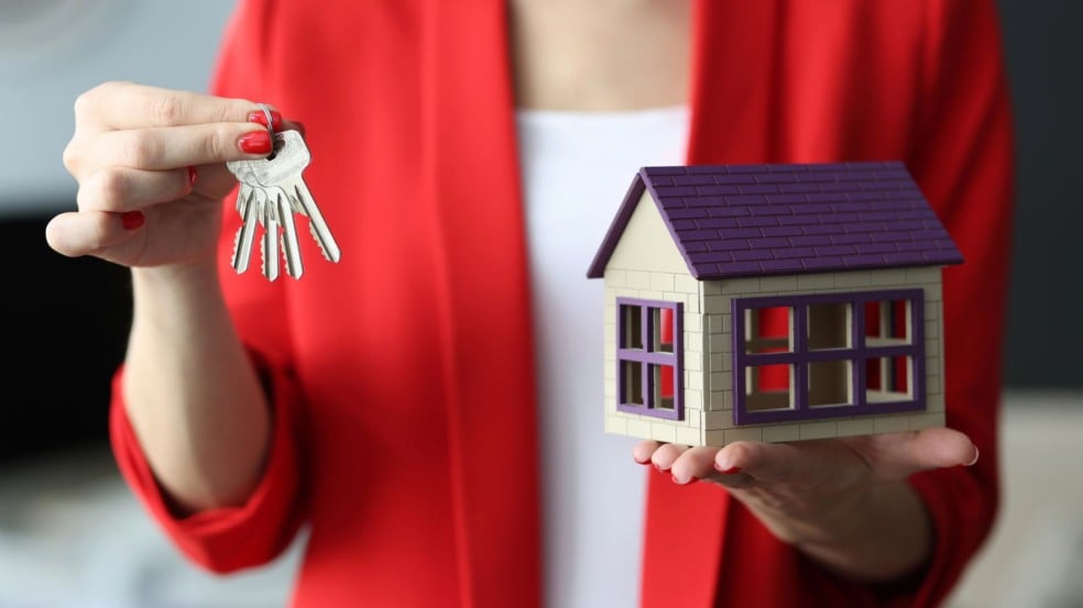 Mulher segurando uma chave e uma casinha em miniatura Mulher segurando uma chave e uma casinha em miniatura