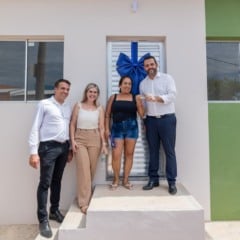 Cerim&ocirc;nia de entrega de moradia popular em Jundia&iacute;, com autoridades e benefici&aacute;ria em frente &agrave; casa.