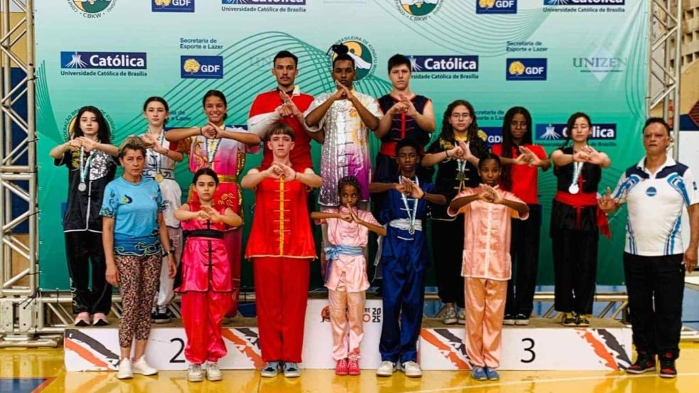 Atletas do time de Jundiaí de kung-fu posam no pódio do Campeonato Brasileiro em Brasília, usando uniformes tradicionais e exibindo medalhas conquistadas na competição. Atletas do time de Jundiaí de kung-fu posam no pódio do Campeonato Brasileiro em Brasília, usando uniformes tradicionais e exibindo medalhas conquistadas na competição.