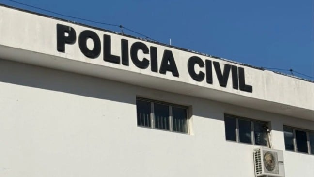Prédio branco da Polícia Civil com letreiro em destaque e céu azul ao fundo.