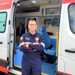 Profissional do SAMU de Jundia&iacute; posa em frente a uma ambul&acirc;ncia de suporte b&aacute;sico com a porta aberta, mostrando o interior do ve&iacute;culo de atendimento de emerg&ecirc;ncia.