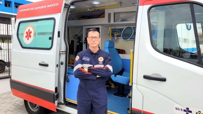 Profissional do SAMU de Jundiaí posa em frente a uma ambulância de suporte básico com a porta aberta, mostrando o interior do veículo de atendimento de emergência.