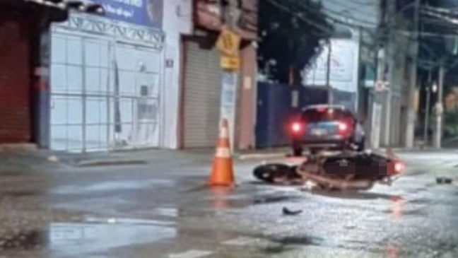 Motocicleta caída no asfalto molhado ao lado de cone de sinalização em cruzamento do Centro de Jundiaí durante a madrugada, após grave acidente de trânsito.