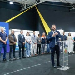 Autoridades e organizadores participam da abertura da FENS em Jundia&iacute;, com discurso em p&uacute;lpito e painel do evento ao fundo.