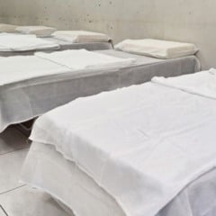 &Aacute;rea interna do abrigo emergencial com v&aacute;rias camas prontas para acolhimento de fam&iacute;lias.