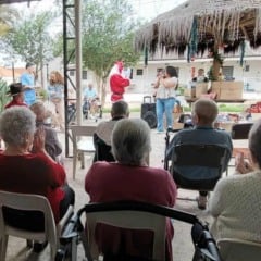 Idosos sentados aplaudem a&ccedil;&atilde;o solid&aacute;ria com Papai Noel durante entrega de presentes da campanha Adote um Vov&ocirc; na Cidade Vicentina, em Jundia&iacute;.