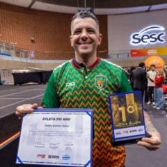 Atleta segurando trof&eacute;u de primeiro lugar e certificado do Pr&ecirc;mio Atleta do Ano 2025 no gin&aacute;sio do SESC Jundia&iacute;.