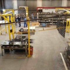 Interior de f&aacute;brica em Jundia&iacute; mostra &aacute;rea de produ&ccedil;&atilde;o industrial com funcion&aacute;rios trabalhando, esteiras, estruturas met&aacute;licas e organiza&ccedil;&atilde;o de materiais.