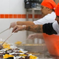 Funcion&aacute;rios do Bom Prato servem refei&ccedil;&otilde;es quentes em marmitas em cozinha industrial durante o preparo dos almo&ccedil;os.