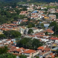Vista aérea de Cabreúva, com casas de telhados vermelhos, uma igreja central e áreas verdes ao fundo, mostrando a integração da cidade com o entorno natural.