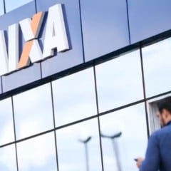 Fachada de agência da Caixa com o logotipo em destaque; homem de costas se aproxima da entrada.