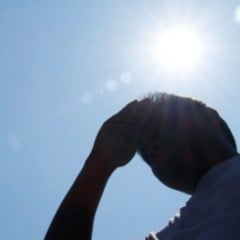 Pessoa se protege do sol sob c&eacute;u azul durante forte onda de calor.