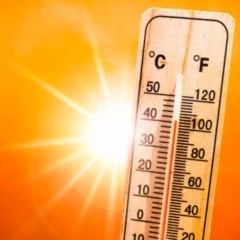 Term&ocirc;metro marcando quase 40 &deg;C sob sol forte e c&eacute;u alaranjado, representando calor intenso e altas temperaturas.