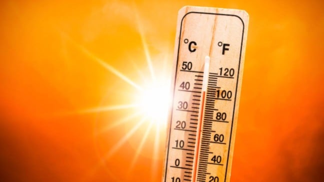 Termômetro marcando quase 40 °C sob sol forte e céu alaranjado, representando calor intenso e altas temperaturas.