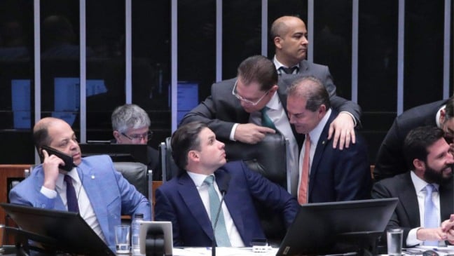Deputados reunidos no plenário da Câmara conversam e trocam cumprimentos durante a sessão, com alguns sentados diante dos computadores e outros fazendo articulações de pé atrás das cadeiras.