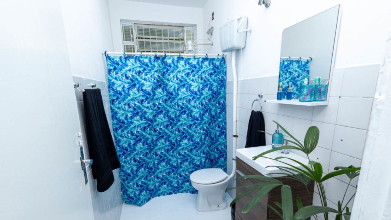Banheiro da Casa da Família com cortina azul estampada, pia com espelho e decoração simples. Banheiro da Casa da Família com cortina azul estampada, pia com espelho e decoração simples.