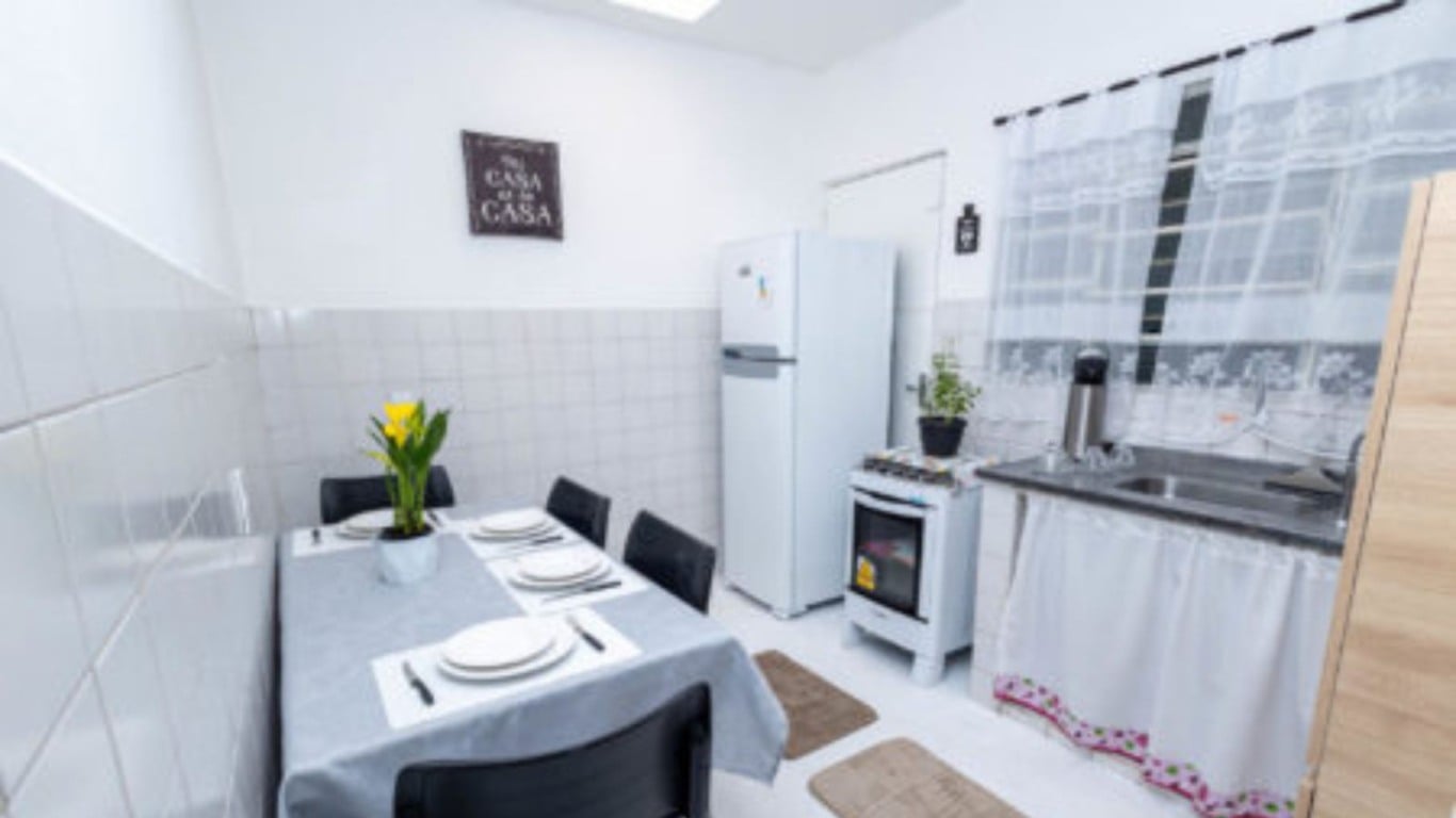 Cozinha da Casa da Família com mesa posta, geladeira, fogão e pia, em ambiente claro e organizado. Cozinha da Casa da Família com mesa posta, geladeira, fogão e pia, em ambiente claro e organizado.