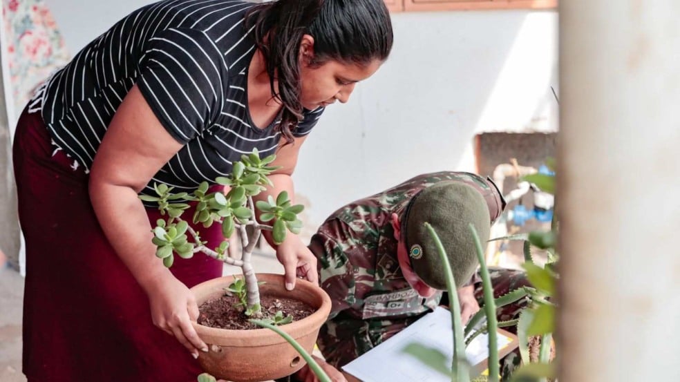 Moradora segura vaso de planta enquanto agente da Prefeitura e soldado do Exército verificam possíveis focos de dengue durante ação casa a casa em Jundiaí. Moradora segura vaso de planta enquanto agente da Prefeitura e soldado do Exército verificam possíveis focos de dengue durante ação casa a casa em Jundiaí.