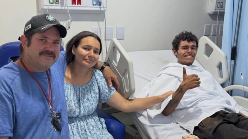 Jovem resgatado após se perder na Serra do Japi aparece deitado em leito hospitalar ao lado de familiares, consciente e fazendo sinal de positivo. Jovem resgatado após se perder na Serra do Japi aparece deitado em leito hospitalar ao lado de familiares, consciente e fazendo sinal de positivo.