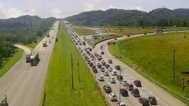 Tráfego intenso em rodovia do Sistema Anchieta-Imigrantes, com longa fila de veículos descendo a serra rumo ao litoral paulista.