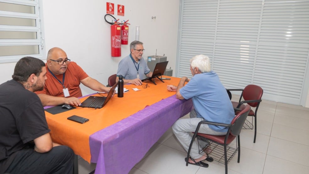 Homens atendem candidatos em uma mesa com computadores durante processo seletivo do programa Emprega+ no CRAS Sul, em Jundiaí. Homens atendem candidatos em uma mesa com computadores durante processo seletivo do programa Emprega+ no CRAS Sul, em Jundiaí.