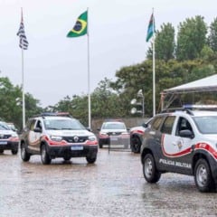 Comboio de viaturas da Polícia Militar chegando ao Paço Municipal de Jundiaí sob chuva durante a cerimônia de entrega.