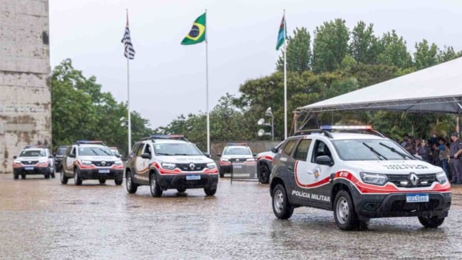 Comboio de viaturas da Polícia Militar chegando ao Paço Municipal de Jundiaí sob chuva durante a cerimônia de entrega.