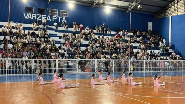 Crianças do balé se apresentam no centro da quadra diante do público.