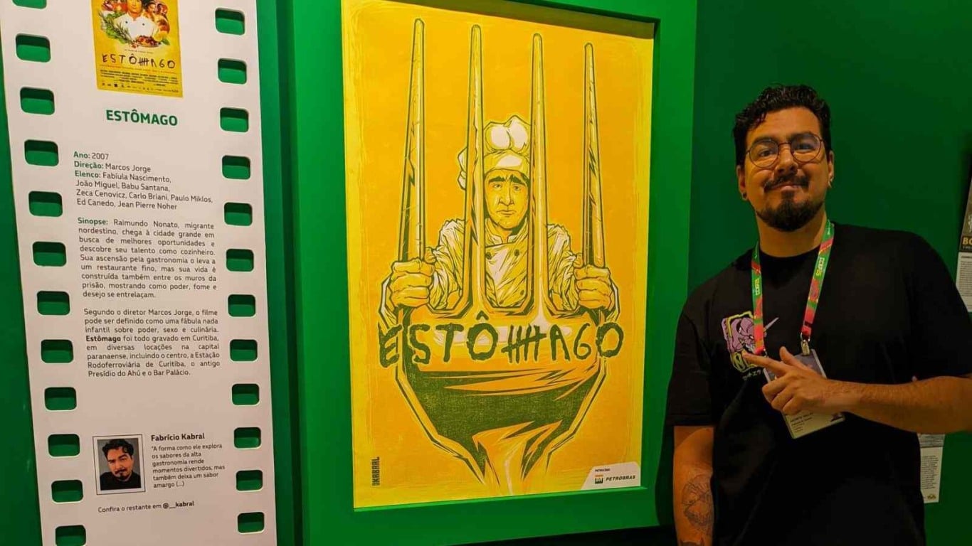 Ilustrador Fabrício Kabral posa ao lado de ilustração inspirada no filme Estômago, exibida na CCXP 2025. Ilustrador Fabrício Kabral posa ao lado de ilustração inspirada no filme Estômago, exibida na CCXP 2025.
