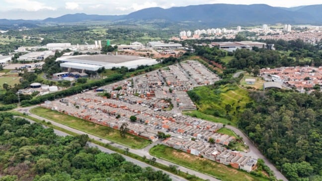 Vista aérea de conjunto habitacional na Fazenda Grande, em Jundiaí, com casas alinhadas, ruas internas e áreas verdes ao redor.
