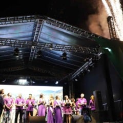 Autoridades e organizadores no palco da Expo Uva durante cerimônia de abertura noturna, com fogos de artifício ao fundo e público acompanhando o evento.