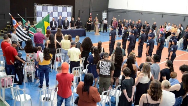 Formandos da Guarda Municipal perfilados durante cerimônia de formatura no Espaço Cidadania, com autoridades e público acompanhando o evento.