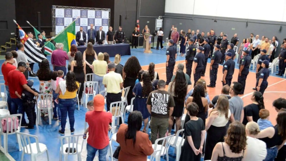 Formandos da Guarda Municipal perfilados durante cerimônia de formatura no Espaço Cidadania, com autoridades e público acompanhando o evento. Formandos da Guarda Municipal perfilados durante cerimônia de formatura no Espaço Cidadania, com autoridades e público acompanhando o evento.