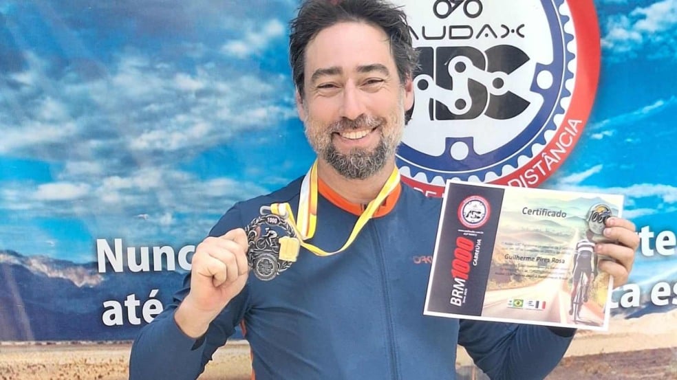Barítono Guilherme Rosa segurando medalha e certificado após completar a prova BRM 1000 de Cabreúva, diante de painel do Audax ABC. Barítono Guilherme Rosa segurando medalha e certificado após completar a prova BRM 1000 de Cabreúva, diante de painel do Audax ABC.
