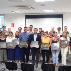 Grupo de representantes municipais e profissionais de cultura e turismo posando em uma sala de eventos, cada um segurando o livro Circuito das Frutas – História, Cultura e Turismo, durante o lançamento oficial da obra.